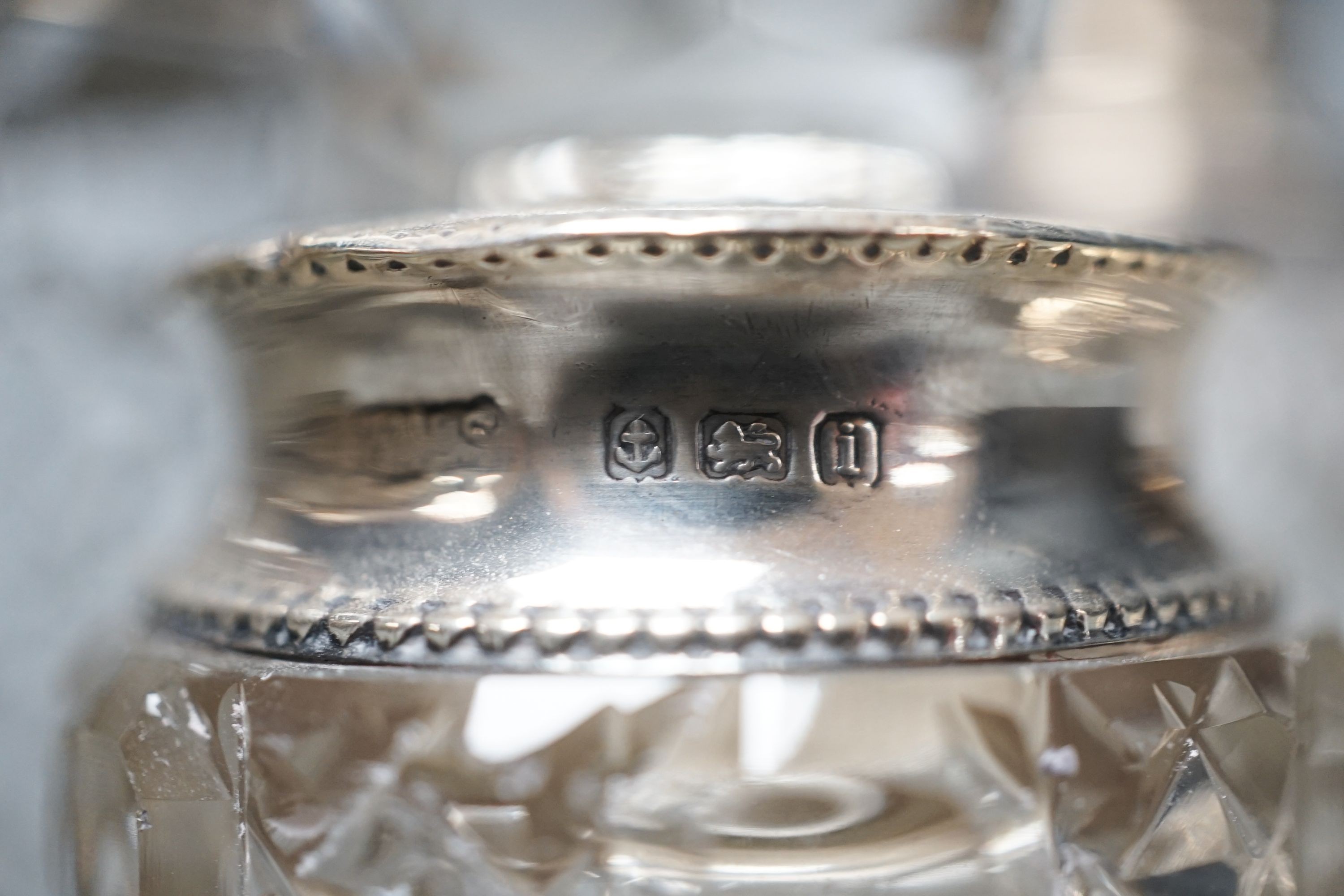 A circular embossed silver box and six silver mounted glass toilet bottles.